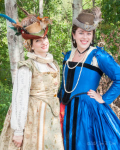 Two smiling women pose in renaissance gowns