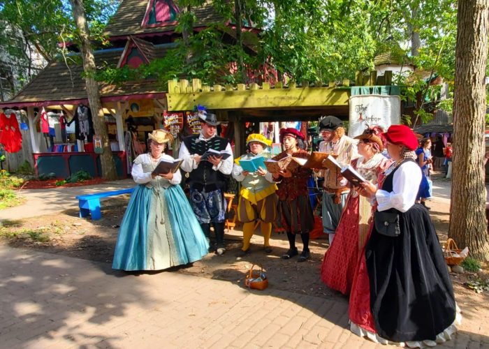 A group of people singing while dressed in 16th century European clothing